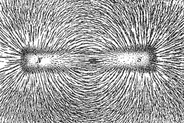 A photo of a bar magnet covered with iron filings showing the magnetic field lines.