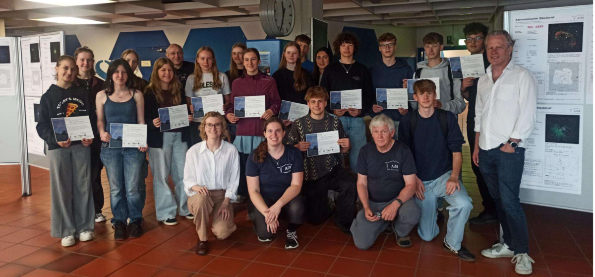 A group photo from the opening of the exhibition “Beyond the Horizon.” It shows Anja Holm from the Institute for Planetology, Tabea Mann and Paul Breitenstein from AiM, and Guido Meyer from MAG. They stand and kneel beside the students’ work at the start of the public event.