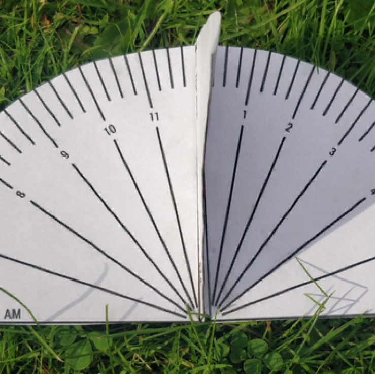 A paper sundial lying on the grass