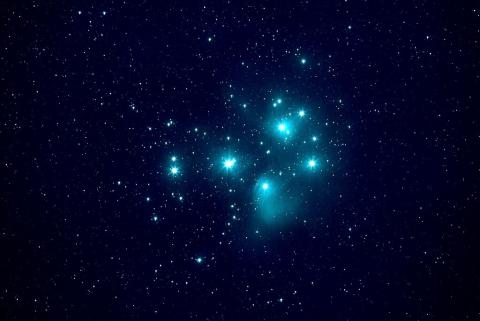A photograph of the Pleiades star cluster showing a group of close bright blue stars.