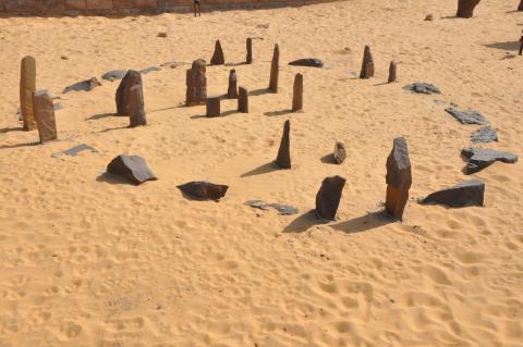 Ancient stone circle in the desert at Nabta Playa, Egypt. Upright stones form a circular pattern on sandy ground, thought to have been used for astronomical or ceremonial purposes thousands of years ago.