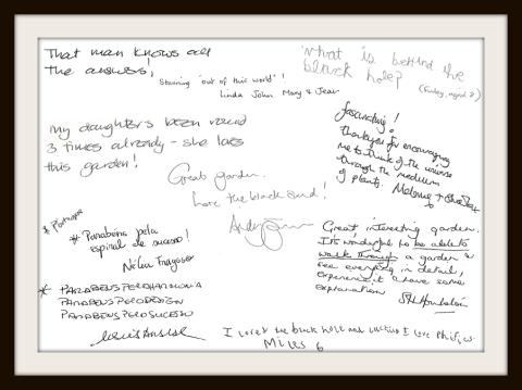 A framed collection of handwritten visitor comments praising a science-themed garden, with notes expressing fascination, curiosity, and enjoyment from both adults and children.