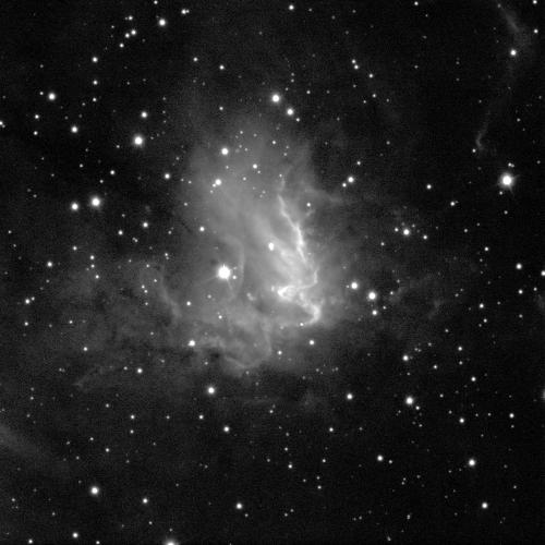 A nebula in various shades of grey against a black background with some white dots of stars scattered around. A few shine brightly inside the nebula as well.