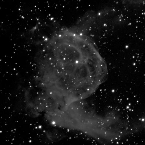 A wispy, grey cloud-like shape against a black background with small dots of white stars. The cloud is circular in the middle, and has two protrusions pointing towards the upper and lower right.