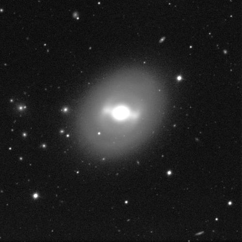 A spiral galaxy against a black background with a few dots of white stars. The galaxy resembles a circle, the centre shining a bright white. A grey, dusty, spherical cloud surrounds the galaxy's centre.
