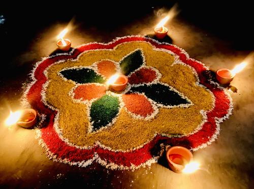 An intricate, floral-like pattern created out of colored sand. Five flaming clay pots sit around the edge, and there is one placed in the middle.