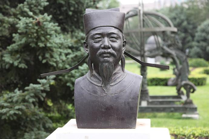 A bronze bust of Shen Kuo with a garden in the background