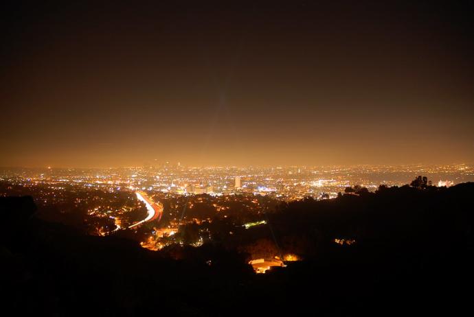 A photo looking down over Hollywood, USA. There are lots of orange lights in the town and the sky has an orange glow.