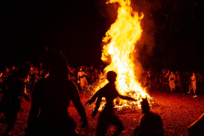 A picture of a large bonfire with many people gathered around.